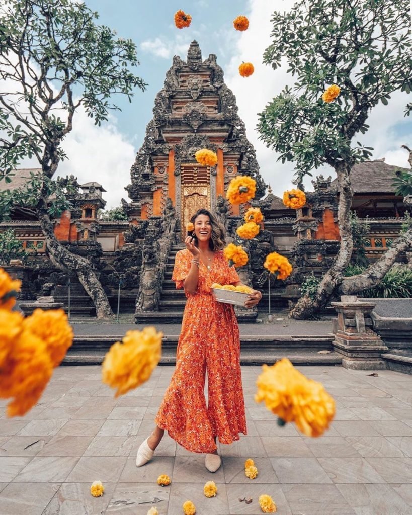 Woman throwing marigold flowers at Bali temple